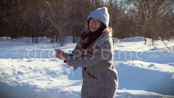 快乐的女孩享受阳光明媚的冬日她朝他的朋友扔雪球视频的预览图