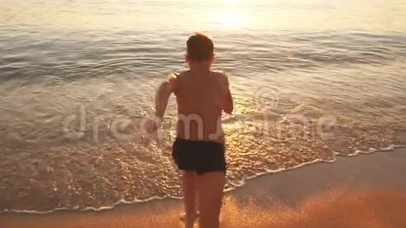 小男孩从海滩跑到海里慢动作视频的预览图