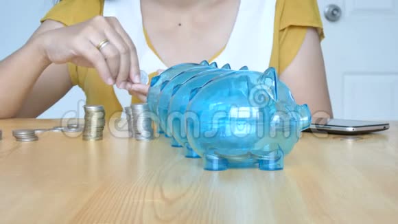 女人的手把钱币放到4个透明的储蓄罐里用空白的比喻把钱分开用于消费和储蓄视频的预览图