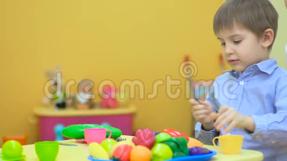 快乐的小男孩在桌旁玩塑料餐具视频的预览图