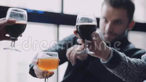 三个穿着休闲装的有魅力的年轻人叮当作响喝着啤酒周末活动视频的预览图