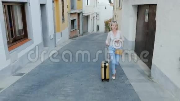 带着旅行袋的女游客沿着西班牙古老的欧洲城市狭窄的街道走去视频的预览图