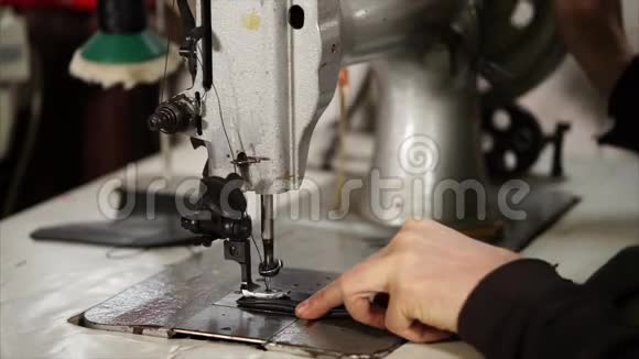 老主人正在用老式工业缝纫机在皮带上缝针视频的预览图