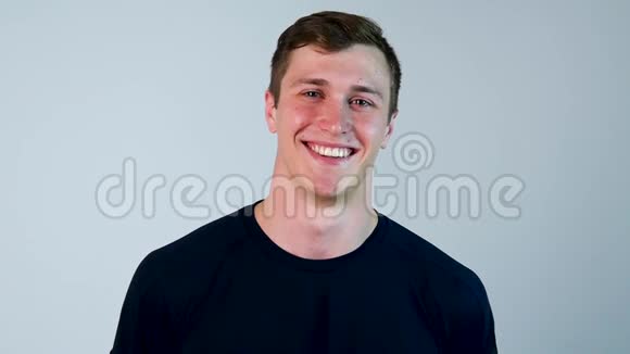年轻的西班牙裔男子穿着蓝色t恤站着笑着在白色背景下孤立地站着笑声概念视频的预览图