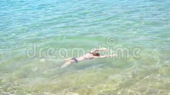 一个小女孩趴在海里把脚和手放在水里视频的预览图