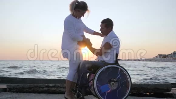 残疾配偶在轮椅上与怀孕女性在日落时残疾男子在轮椅上抚摸妇女视频的预览图