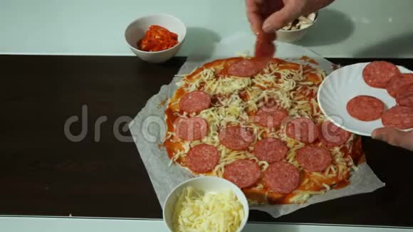 厨师把意大利腊肠放在生披萨的奶酪上视频的预览图