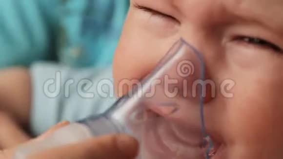 一个小男孩哭的时候妈妈戴上吸入器面罩的脸治疗咳嗽吸入程序视频的预览图