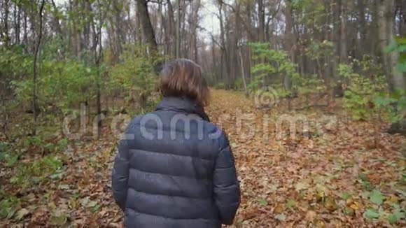 老妇人沿着秋天的森林走在小径上视频的预览图