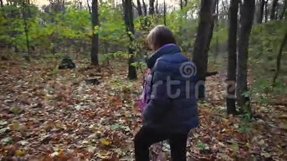 在一个美好的日子里老妇人在秋天的森林里散步视频的预览图