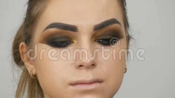 专业的化妆师为一个有绿色眼睛的漂亮模特做了一双烟熏的棕色眼睛视频的预览图