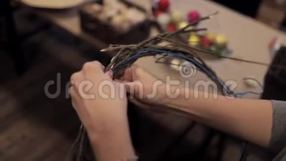 女性的双手用铁丝把木棒绑在圣诞花环上视频的预览图