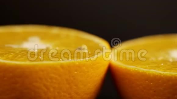 两半的橙色躺在黑色的背景上绕着自己旋转黑色背景圈的鲜橙色视频的预览图