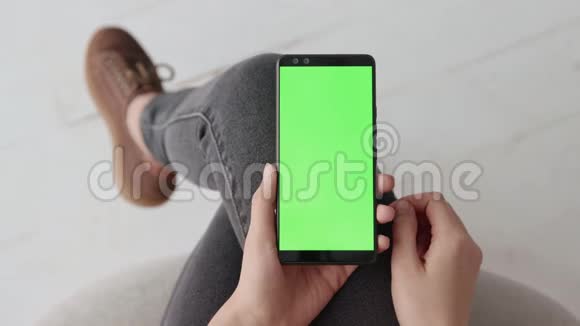 Chroma键模型与绿色屏幕上的年轻女子在家里的手机视频的预览图