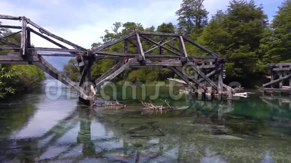 森林中绿色水晶河上的老木桥阿根廷巴里洛切附近视频的预览图