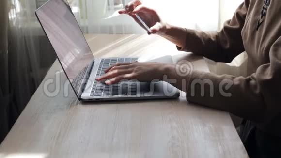 女人在笔记本电脑上打字手里拿着信用卡视频的预览图