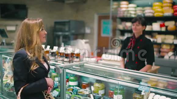 卖家帮助漂亮的金发女郎选择超市里的酱汁视频的预览图