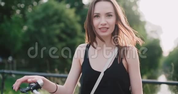 城市街道上骑自行车的快乐微笑的年轻女子的肖像视频的预览图