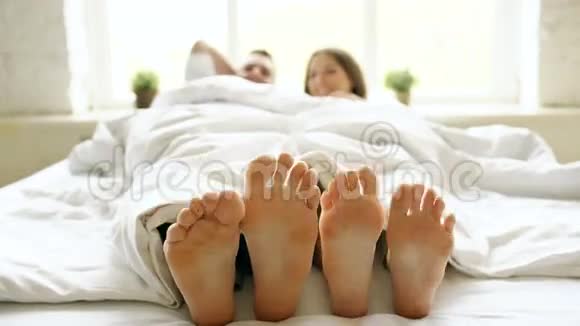 一对年轻美丽有爱心的夫妇在早晨起床时在毯子下玩耍跳舞视频的预览图