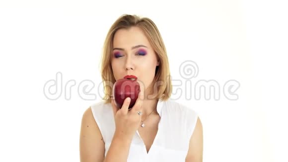 一个年轻的女人咬了一口苹果白底视频视频的预览图
