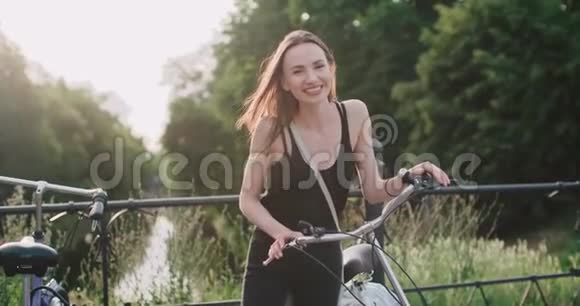 城市街道上骑自行车的快乐微笑的年轻女子的肖像视频的预览图