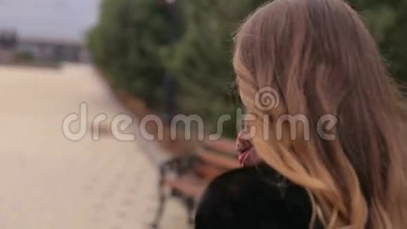 一个穿着黑色外套在公园散步的漂亮女孩的特写肖像视频的预览图