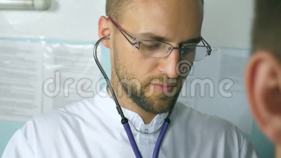 英俊的医生用听诊器检查病人的肖像年轻医务工作者倾听病人心跳视频的预览图