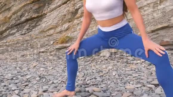 女孩在岩石背景上做呼吸练习时蹲着身体反射特写腹部和身体视频的预览图