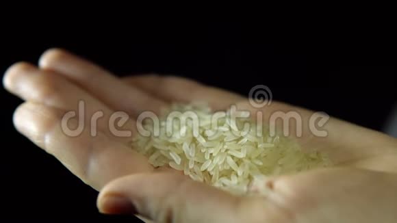女性手指的特写在黑色背景上用手搅拌米饭视频的预览图
