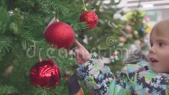 父子俩在商店里选一棵圣诞树在圣诞节前出售玩具和圣诞树视频的预览图