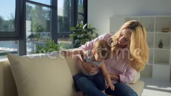 漂亮的妈妈和孩子坐在沙发上视频的预览图