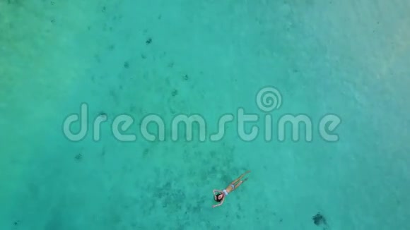 一个迷人的女人穿着比基尼漂浮在清澈的大海上的空中景色在印度游泳的漂亮姑娘视频的预览图
