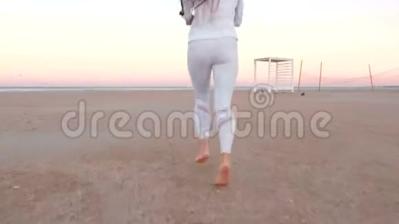 秋日日出时年轻女子正在海边的沙滩上慢跑后景视频的预览图