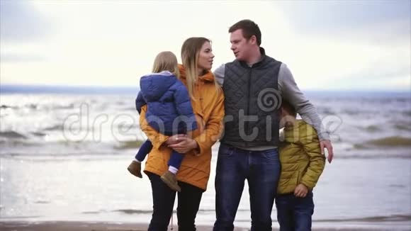 丈夫和妻子和孩子们一起站在海边享受这一天视频的预览图