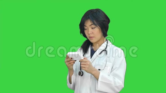 亚洲女医生读处方看绿色屏幕上的医药盒Chroma键视频的预览图