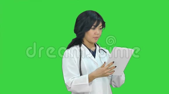 女医生拿着数码平板电脑演示项目观看绿色屏幕上的摄像机Chroma键视频的预览图