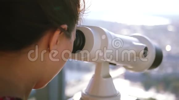 一个女孩用望远镜从高处看城市下面的动作高清1920x1080视频的预览图