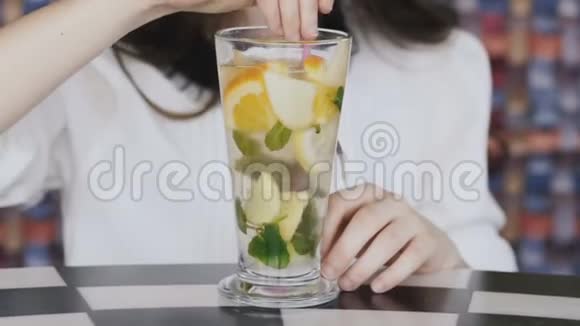 美丽的女孩用小管搅拌柠檬水对着镜头微笑视频的预览图