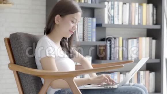 美丽的自由职业年轻的亚洲女性在网上工作手提电脑坐在客厅的沙发上视频的预览图