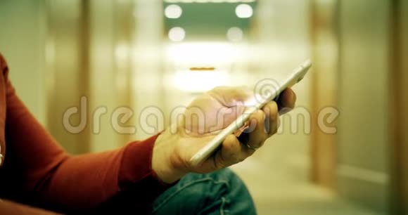 穿休闲服装的男人在酒店走廊里用智能手机视频的预览图