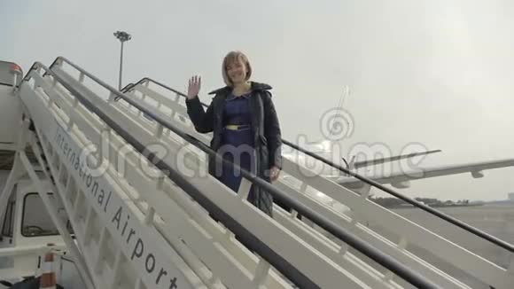 微笑的空姐站在飞机的梯子上视频的预览图