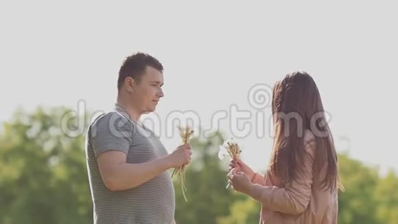 一对浪漫的夫妇在夏天在阳光下的草地上吹着一束蒲公英爱一起快乐视频的预览图