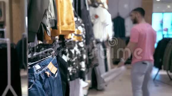 时尚的年轻人在商店里挑选衣服男性顾客购物视频的预览图