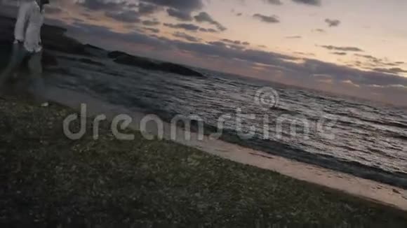 年轻人在海滩上散步享受傍晚的海景视频的预览图