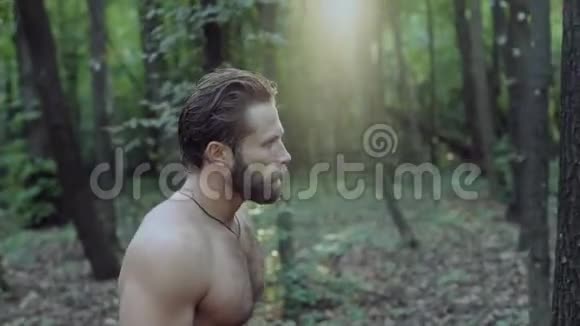 英俊的长胡子的人带着斧头在森林里散步4K视频的预览图