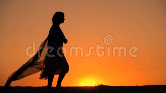 年轻女孩在夕阳下散步的剪影视频的预览图