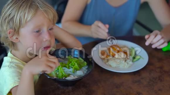 一位年轻女子和她儿子在一家街头咖啡馆里吃中国菜的慢镜头视频的预览图