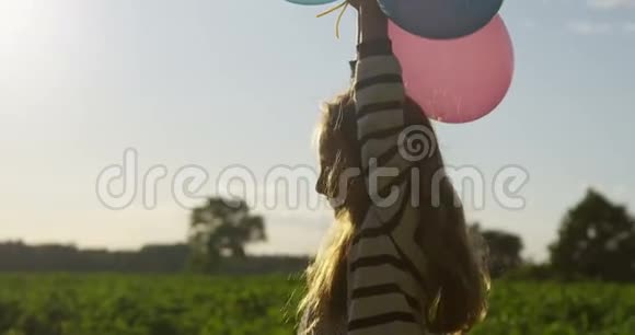 微笑的小女孩手里拿着气球在户外慢动作视频的预览图