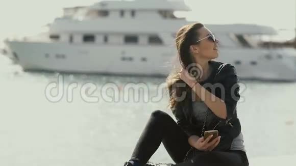 一个美丽的女孩坐在海边的码头上视频的预览图