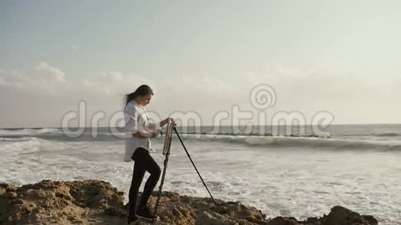年轻女子正在画海岸边的画架上视频的预览图
